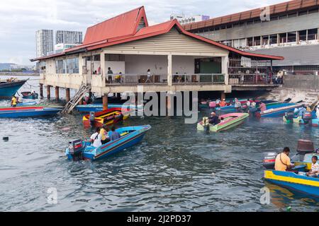 Kota Kinabalu, Malesia - 23 marzo 2019: Barche a motore con passeggeri sono vicino al mercato del pesce KK in una giornata di sole, a buon mercato mezzi di trasporto pubblico tra islan Foto Stock