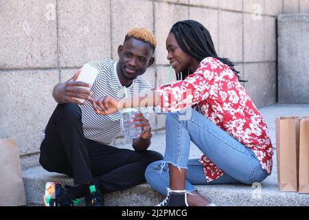 Giovane coppia nera felice prendendo un selfie, bere rinfreschi. Foto Stock