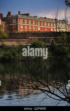 Il tipico Tudor incontrò il barocco quando Sir Christopher Wren costruì un imponente palazzo dal 1689 per i monarchi congiunti Guglielmo III e Maria II sul sito di Hampton Court accanto al Tamigi nel borgo londinese di Richmond-upon-Thames, Inghilterra, Regno Unito. Wren ha conservato quasi tutto il palazzo reale Tudor originale con i suoi camini in mattoni rossi sgargianti, mescolandolo con un design più sobrio con finestre circolari, bandiere decorative e una balaustra sul tetto. Foto Stock