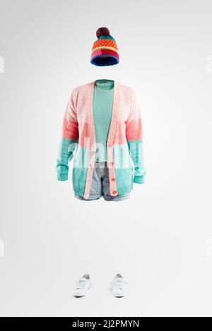 Come sapete im non realmente qui. Studio girato di una donna invisibile indossando abbigliamento invernale in piedi su uno sfondo grigio. Foto Stock