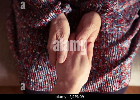Primo piano foto delle mani di una donna anziana che tiene le mani di una giovane donna Foto Stock