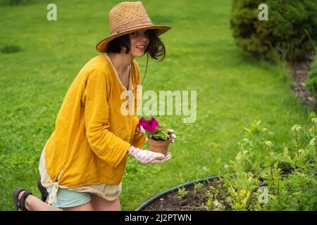 Una ragazza sta per piantare un fiore nel suo giardino. Foto Stock
