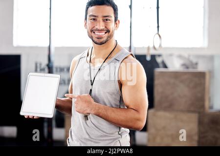 Voglio che io sia nel tuo angolo. Scatto di un bel ragazzo utilizzando un tablet digitale in palestra. Foto Stock