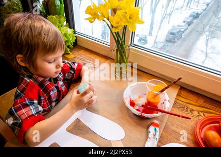 Ragazzo che attira le orecchie di un coniglietto pasquale fatto a mano in cartone. Preparazione per la celebrazione della Pasqua. Foto Stock