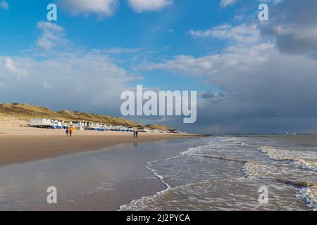 Camminatori che passano cabine sulla spiaggia di Dishoek, Zeeland Province, Olanda. Foto Stock