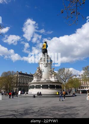 Monumento alla Repubblica, adornato con un gilet giallo e blu nei colori della bandiera Ucraina, insieme con il simbolo della ribellione di estinzione, movimento internazionale sociale ambientale, in protesta della guerra in Ucraina e l'uso eccessivo di petrolio e il suo ruolo nella distruzione del clima. 2 aprile 2022, Parigi, Francia Foto Stock