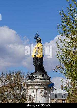 Monumento alla Repubblica, adornato con un gilet giallo e blu nei colori della bandiera Ucraina, insieme con il simbolo della ribellione di estinzione, movimento internazionale sociale ambientale, in protesta della guerra in Ucraina e l'uso eccessivo di petrolio e il suo ruolo nella distruzione del clima. 2 aprile 2022, Parigi, Francia Foto Stock