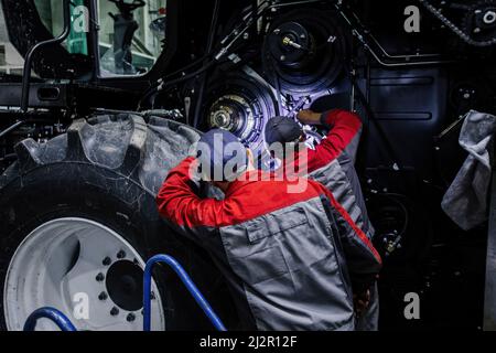 Addetti alla manutenzione che riparano la trebbiatrice agricola in officina Foto Stock