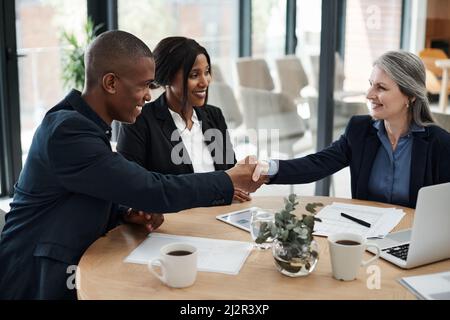 Fare affari bene è la via da seguire. Shot di una donna d'affari matura che agita le mani con un collega in un ufficio moderno. Foto Stock