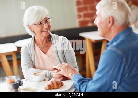 Theyve si mantenne l'altra azienda nel corso degli anni. Shot di una felice coppia senior che si rilassa con una tazza di caffè in una caffetteria. Foto Stock