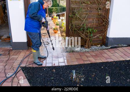 Operaio pulizia vialetto con benzina idropulitrice spruzzi la sporcizia, servizi di pulizia professionale.pulizia ad alta pressione, corpo inferiore. Foto Stock