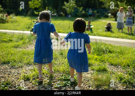 Preschoolers sulla strada. Le ragazze stanno camminando per strada. Vacanze con bambini in estate. I bambini in abiti identici stanno tenendo le mani Foto Stock