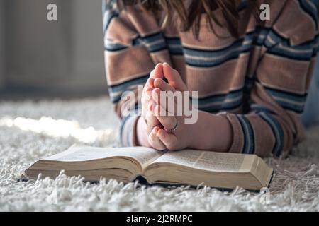 Una giovane donna sta leggendo la Bibbia mentre si trova sul pavimento. Foto Stock