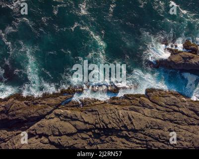 Riprese da un drone. Tempesta sul mare. Le onde bianche e schiumose si infrangono sulla costa rocciosa. Bella stagcape. Immagine a colori. Pubblicità, banner, cartoline. Foto Stock