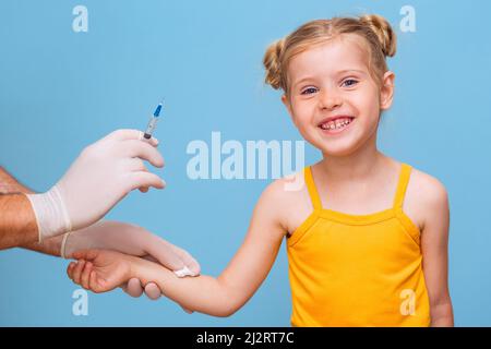 Un medico vaccina una bambina bionda. Foto Stock