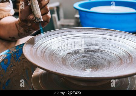 Primo piano di una torcia con fuoco che asciuga il pezzo formato sulla ruota del vasaio. Concetto di artigianale. Foto Stock