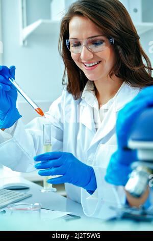 Bella giovane scienziata femminile o ricercatore che lavora in laboratorio con provetta che fa una certa ricerca industria farmaceutica Foto Stock