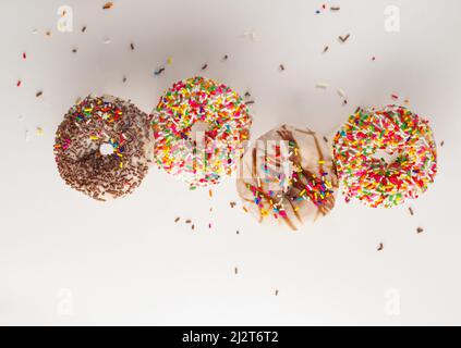 Ciambelle multicolore in glassa di zucchero e cioccolato su sfondo bianco. Non ci sono persone nella foto. Spazio libero da inserire. Supermercato, Foto Stock