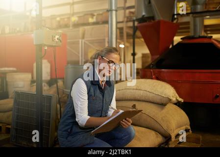 Scendendo alla macinatura quotidiana. Shot di un imprenditore industrioso che lavora da solo nella sua maestria del caffè. Foto Stock
