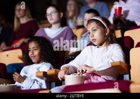Tween ragazza con un amico aframericano che guarda il film al cinema Foto Stock
