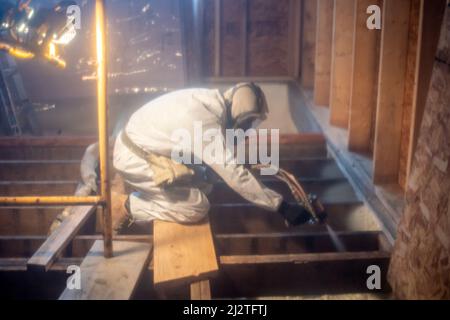 Nov 30 2021 Michigan USA; un lavoratore in abiti protettivi soffia in schiuma isolamento Foto Stock