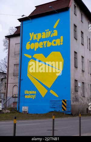 Gdansk Polonia Marzo 2022 UCRAINA TESTO DI COMBATTIMENTO IN GRAFFITI con grande cuore in colori di bandiera ucraini. Murale dipinto in casa di costruzione Polonia Gdansk Europa concetto di solidarietà e sostegno con l'Ucraina Foto Stock