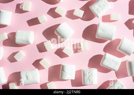 Marshmallow bianco, a cubetti di zucchero, su sfondo rosa, con ombre dure. La capacità di utilizzare come sfondo, il concetto del winte Foto Stock