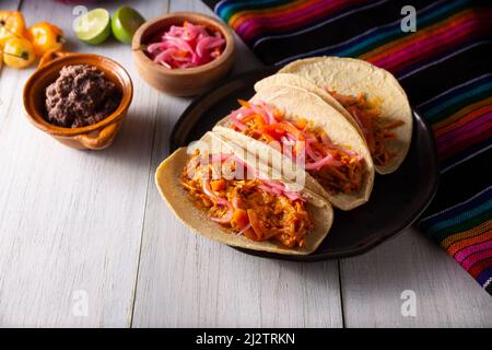 Taco de Cochinita pibil. Tipico stufato messicano di Yucatan, a base di maiale marinato con acionetto e generalmente accompagnato da fagioli e cipolla rossa Foto Stock