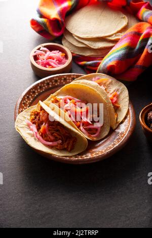 Taco de Cochinita pibil. Tipico stufato messicano di Yucatan, a base di maiale marinato con acionetto e generalmente accompagnato da fagioli e cipolla rossa Foto Stock