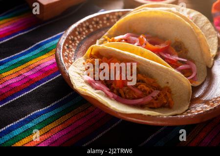 Taco de Cochinita pibil. Tipico stufato messicano di Yucatan, a base di maiale marinato con acionetto e generalmente accompagnato da fagioli e cipolla rossa Foto Stock