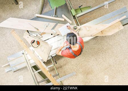 Carpentiere irriconoscibile che prende al telefono vicino alla squadratrice Foto Stock
