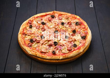 Pizza con vari tipi di salsicce sottili, cetrioli sottaceto, olive e cipolla rossa Foto Stock