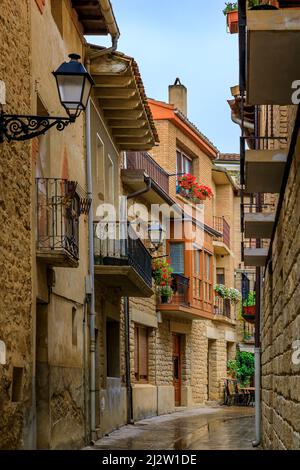 Rustiche case medievali in pietra su una strada di Olite, Spagna famosa per un magnifico castello del Palazzo reale in una giornata piovosa con pozzanghere su ciottoli Foto Stock