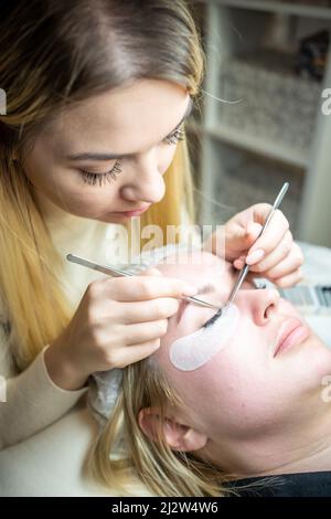 Procedura di estensione delle ciglia nel salone di bellezza. Ciglia da vicino. Concetto spa lash. Foto Stock