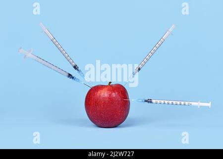 Frutta di mela iniettata con siringhe. Concetto di organismo geneticamente modificato Foto Stock