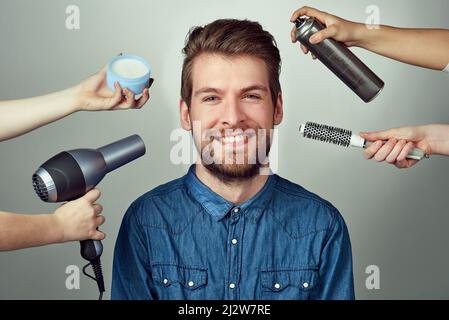 Combina il tuo look con un makeover. Ritratto di studio di un giovane uomo che ottiene un rifacimento dei capelli su uno sfondo grigio. Foto Stock