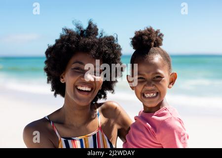 Ritratto di felice madre e figlia afroamericana godendo giorno di sole in spiaggia Foto Stock