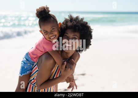 Ritratto di allegra madre e figlia afroamericana godendo in spiaggia in giorno di sole Foto Stock