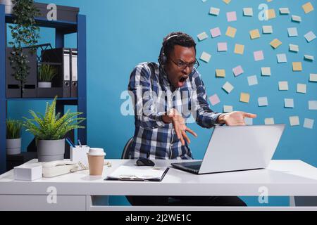 Un rappresentante dell'helpdesk infuriato e infastidito che gestiva in modo aggregato mentre si è in contatto con il cliente che ha un problema. MAD arrabbiato operatore call center urla con rabbia mentre parla con il cliente. Foto Stock