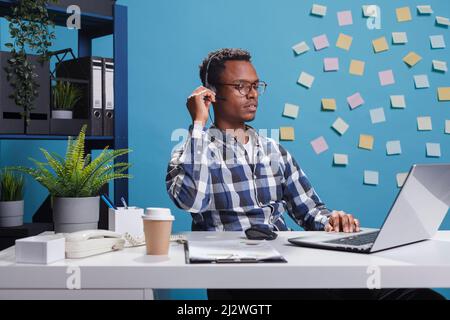 Operatore consulente assistenza clienti al telefono con il cliente che richiede assistenza per la documentazione dell'applicazione. Rappresentante del telemarketing durante una chiamata con la persona mentre si utilizza il laptop di lavoro. Foto Stock
