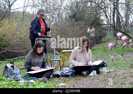 Pittura in un parco. Pittore maschile che dà lezioni di disegno per due ragazze. 20 marzo 2019. Kiev, Ucraina Foto Stock