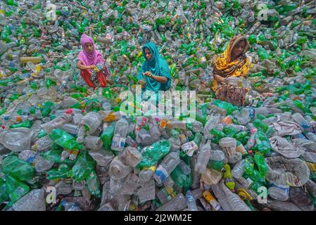 Noakhali, Chittagong, Bangladesh. 4 aprile 2022, Noakhali, Chittagong, Bangladesh: I lavoratori stanno smistando bottiglie di plastica usate in una fabbrica di riciclaggio a Noakhali, Bangladesh. Le bottiglie di plastica utilizzate per l'imballaggio dell'acqua impiegano più di 1.000 anni per biodegradarsi e, se incenerite, producono fumi tossici. I rifiuti galleggianti di plastica, che possono sopravvivere per migliaia di anni in acqua, fungono da mini dispositivi di trasporto per specie invasive, distruggendo gli habitat. La plastica sepolta in profondità nelle discariche può lisciviare sostanze chimiche dannose che si diffondono nelle acque sotterranee. Credit: ZUMA Press, Inc./Alamy Live News Foto Stock