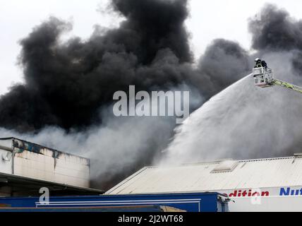 Mulheim, Germania. 04 aprile 2022, Renania settentrionale-Vestfalia, Mülheim an der Ruhr: Il reparto antincendio spegne l'incendio in un magazzino. Un carosello per bambini su un rimorchio per camion aveva preso fuoco per motivi ancora sconosciuti. A causa del forte sviluppo di fumo, i messaggi di avvertimento sono stati pubblicati tramite l'app di avvertimento Nina. Foto: Roland Weihrauch/dpa Credit: dpa Picture Alliance/Alamy Live News Foto Stock