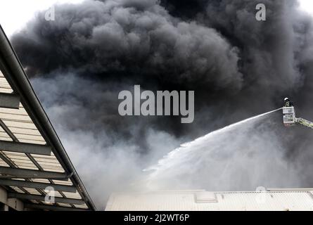 Mulheim, Germania. 04 aprile 2022, Renania settentrionale-Vestfalia, Mülheim an der Ruhr: Il reparto antincendio spegne l'incendio in un magazzino. Un carosello per bambini su un rimorchio per camion aveva preso fuoco per motivi ancora sconosciuti. A causa del forte sviluppo di fumo, i messaggi di avvertimento sono stati pubblicati tramite l'app di avvertimento Nina. Foto: Roland Weihrauch/dpa Credit: dpa Picture Alliance/Alamy Live News Foto Stock