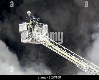 Mulheim, Germania. 04 aprile 2022, Renania settentrionale-Vestfalia, Mülheim an der Ruhr: Il reparto antincendio spegne l'incendio in un magazzino. Un carosello per bambini su un rimorchio per camion aveva preso fuoco per motivi ancora sconosciuti. A causa del forte sviluppo di fumo, i messaggi di avvertimento sono stati pubblicati tramite l'app di avvertimento Nina. Foto: Roland Weihrauch/dpa Credit: dpa Picture Alliance/Alamy Live News Foto Stock