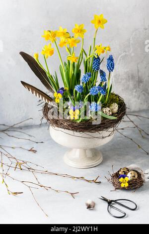 Vita morta con giacinto d'uva blu, narcisi e fiori di viola nel vecchio vaso in ceramica d'annata. Decorazione fatta in casa per Pasqua o primavera floristica A. Foto Stock