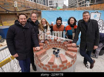 01 aprile 2022, Amburgo: Andreas Dressel (r-l, SPD), Senatore per le Finanze, Mitra Kassai, investitore e fondatore di 'oll Inklusiv', Benjamin Adrion, fondatore dell'organizzazione no-profit Viva con Agua, Carolin Stüdemann del Consiglio Esecutivo Viva con Agua de Sankt Pauli e.V., Oke Göttlich, Presidente FC St. Pauli, E Leon Rosoff, Villa Viva iniziatore e Urban Future Development, si trovano accanto a una fontana durante la posa della pietra di fondazione di 'Villa Viva' nel Münzviertel. L'organizzazione senza scopo di lucro Viva con Agua sta costruendo la 'Villa Viva' la pensione a dodici piani, che deve essere costruita Foto Stock