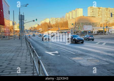 Mosca. Russia. Marzo 22, 2022. Vista delle auto che si muovono lungo la strada della città. Una strada cittadina in primavera sotto un cielo blu nuvoloso. Foto Stock
