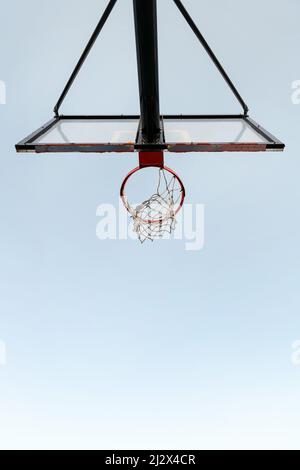 foto verticale di un canestro da basket dal basso con il cielo sullo sfondo, concetto di sport urbano all'aperto, spazio di copia per il testo Foto Stock