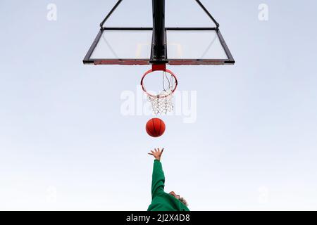 donna latina irriconoscibile che gioca in un campo da basket visto dal basso con il cielo sullo sfondo, concetto di sport urbano all'aperto, spazio copia f Foto Stock